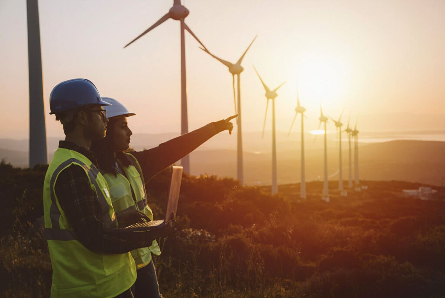 Two Engineers with security hermet in the field of wind turbines.